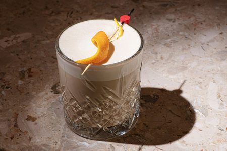 Viski Sour cocktail joka on koristeltu appelsiinin kuorella